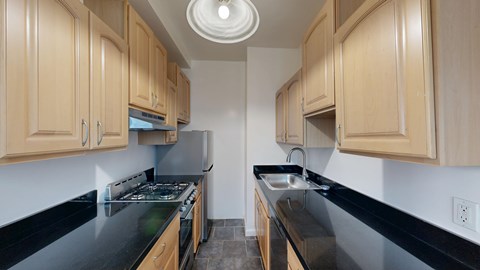 A kitchen with wooden cabinets and black countertops.