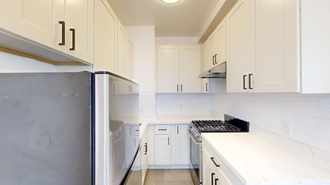 A kitchen with white cabinets and a black refrigerator.
