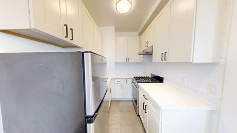 A kitchen with white cabinets and a black fridge.