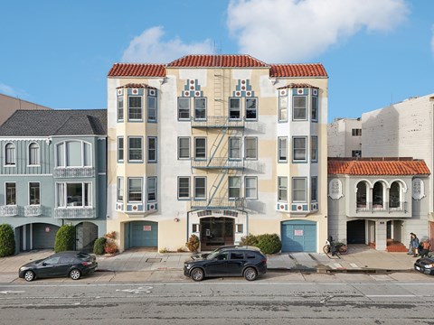 A row of three-story buildings with balconies and garage doors.