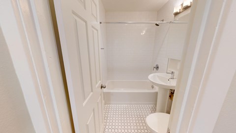 A white bathroom with a shower, sink and toilet.
