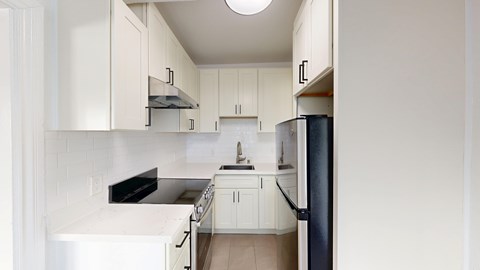 A kitchen with white cabinets and a black refrigerator.