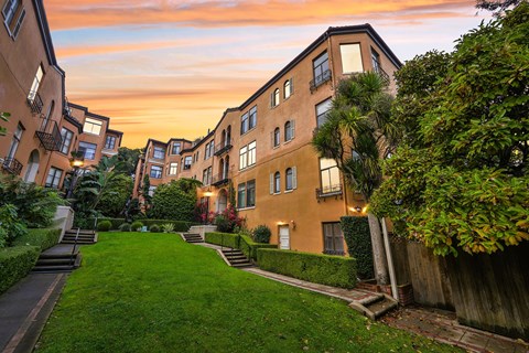 A sunset view of a residential area with apartment buildings and green lawns.