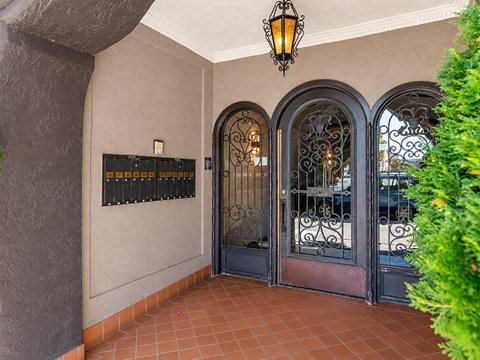 A building entrance with a black gate and a lantern hanging from the ceiling.
