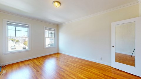 A room with wooden floors and two windows.
