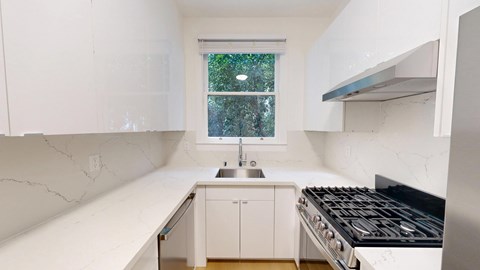 A white kitchen with a window and a stove.