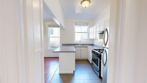 A kitchen with white cabinets and a stove top oven.