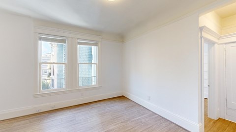 A room with a window and wooden flooring.