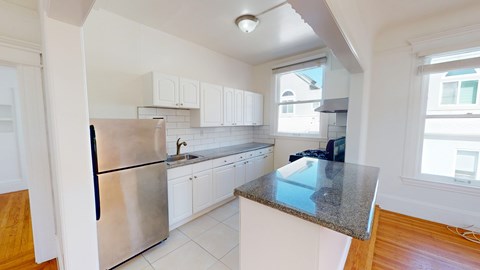 A kitchen with a stainless steel refrigerator and white cabinets.