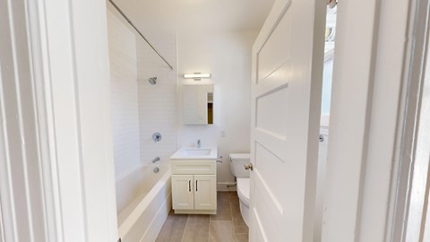 A white bathroom with a tub, sink, and toilet.