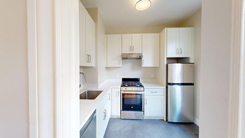 A kitchen with white cabinets and a stainless steel refrigerator.