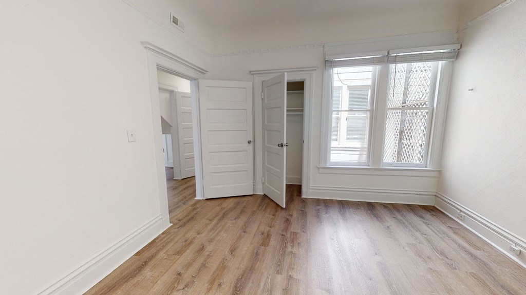 a living room with wood floors and white walls and a door to a closet