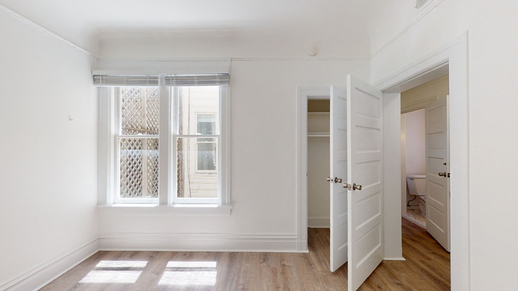 a living room with white walls and a door to a closet and a window