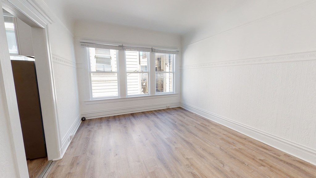 an empty room with wood floors and a window