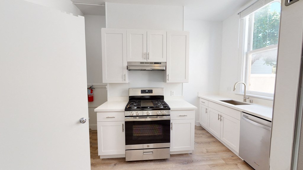 a white kitchen with a stove and white cabinets