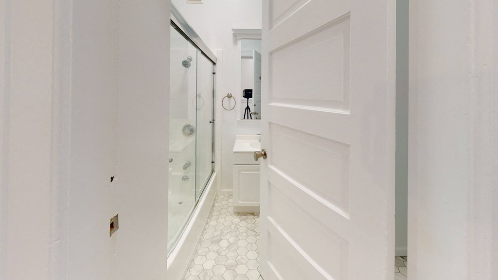 a white bathroom with a shower and a white door