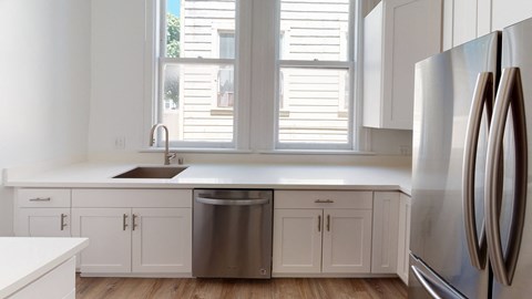 a kitchen with white cabinets and stainless steel appliances and windows