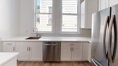 a kitchen with white cabinets and stainless steel appliances and windows