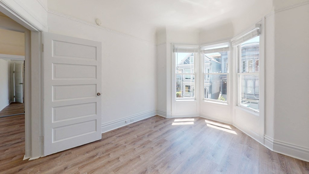 a living room with white walls and wood floors and a white door