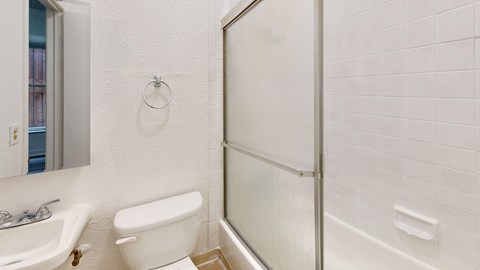 A white bathroom with a toilet, sink, and shower.