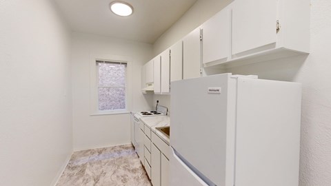 A kitchen with white cabinets and a fridge.