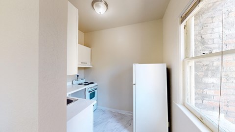 A small kitchen with a white fridge and a window.
