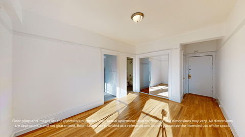 A spacious room with wooden floors and white walls.