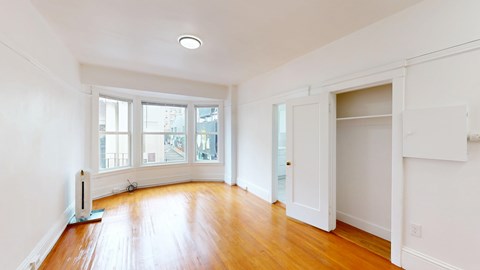 A room with a wood floor and a window overlooking a street.