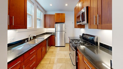A kitchen with wooden cabinets and a stainless steel refrigerator.