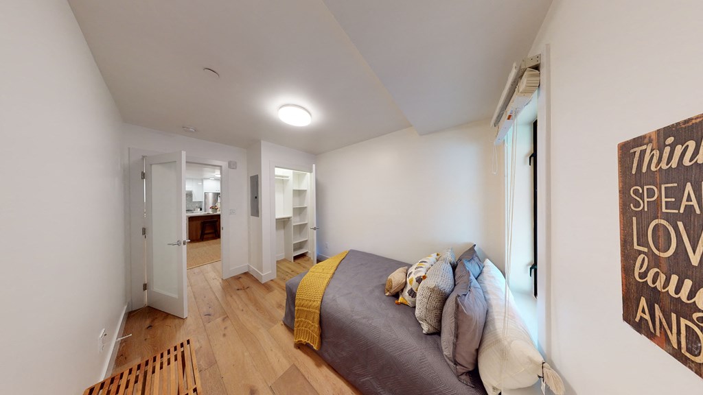 Spacious bedroom with a sitting bench, bed, windows and closet