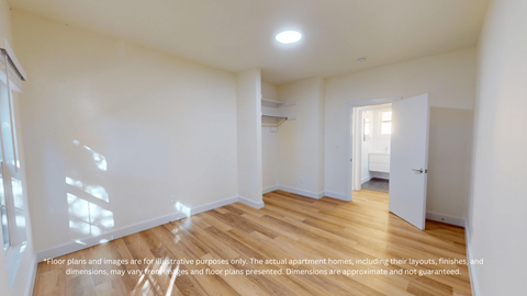 A spacious room with wooden flooring and white walls.