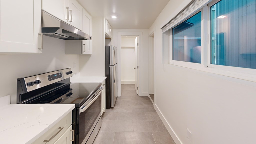 A kitchen with white cabinets and black appliances.