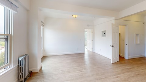 A spacious room with wooden floors and white walls.
