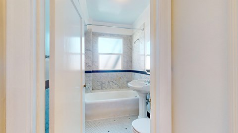 A white bathroom with a tub, toilet and sink.