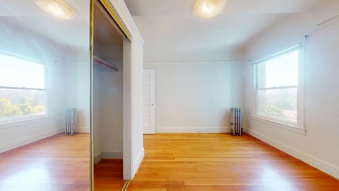 A room with wooden floors and white walls, with a door on the left side.
