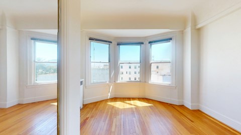 A room with wooden floors and three windows.