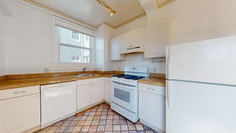 A kitchen with white appliances and brown tiles.