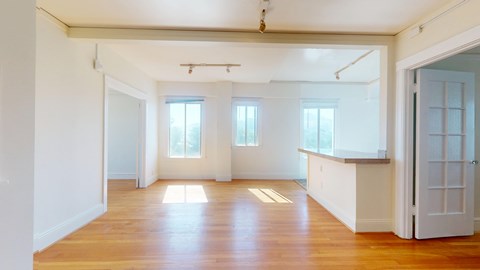 A large empty room with wooden floors and white walls.