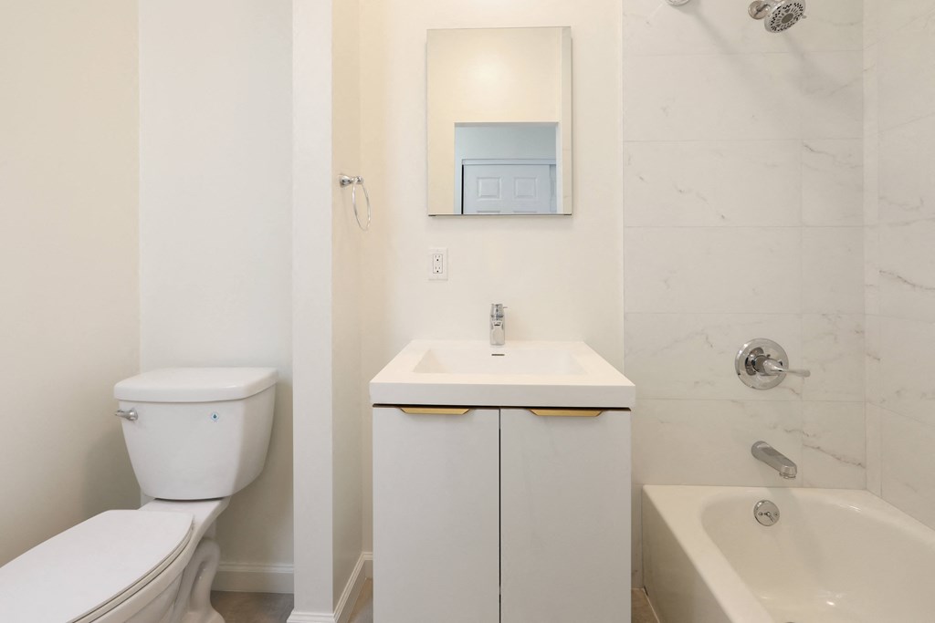 a bathroom with a toilet sink and tub and a mirror