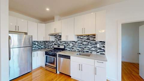 A kitchen with white cabinets and a black and white backsplash.