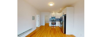 a renovated kitchen with white cabinets and a stainless steel refrigerator