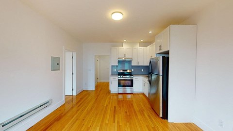 a renovated kitchen with white cabinets and a stainless steel refrigerator