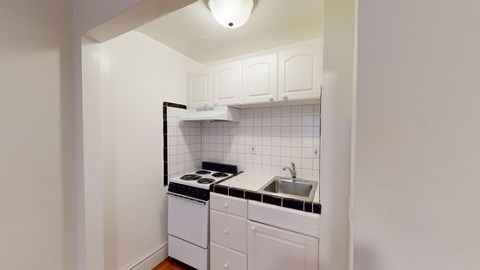 A small kitchen with white appliances and a black stove top.