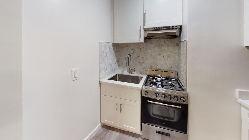 a kitchen with white cabinets and a stove and a sink