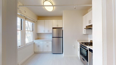 A kitchen with white cabinets and a stainless steel refrigerator.