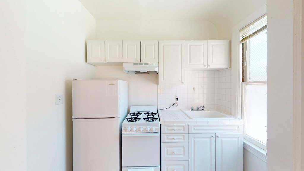 A white kitchen with a stove, oven, and cabinets.