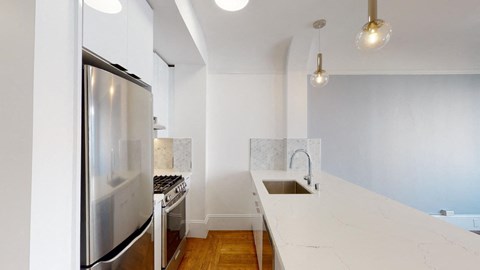a kitchen with white counter tops and a stainless steel refrigerator