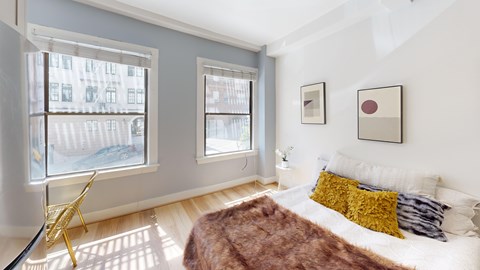 A bedroom with a bed, a chair, and two pictures on the wall.