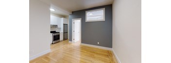 a renovated living room and kitchen with wood floors and a grey wall