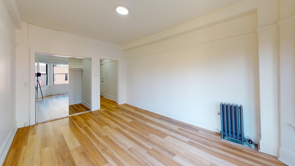 a living room with wood floors and white walls and a blue heater